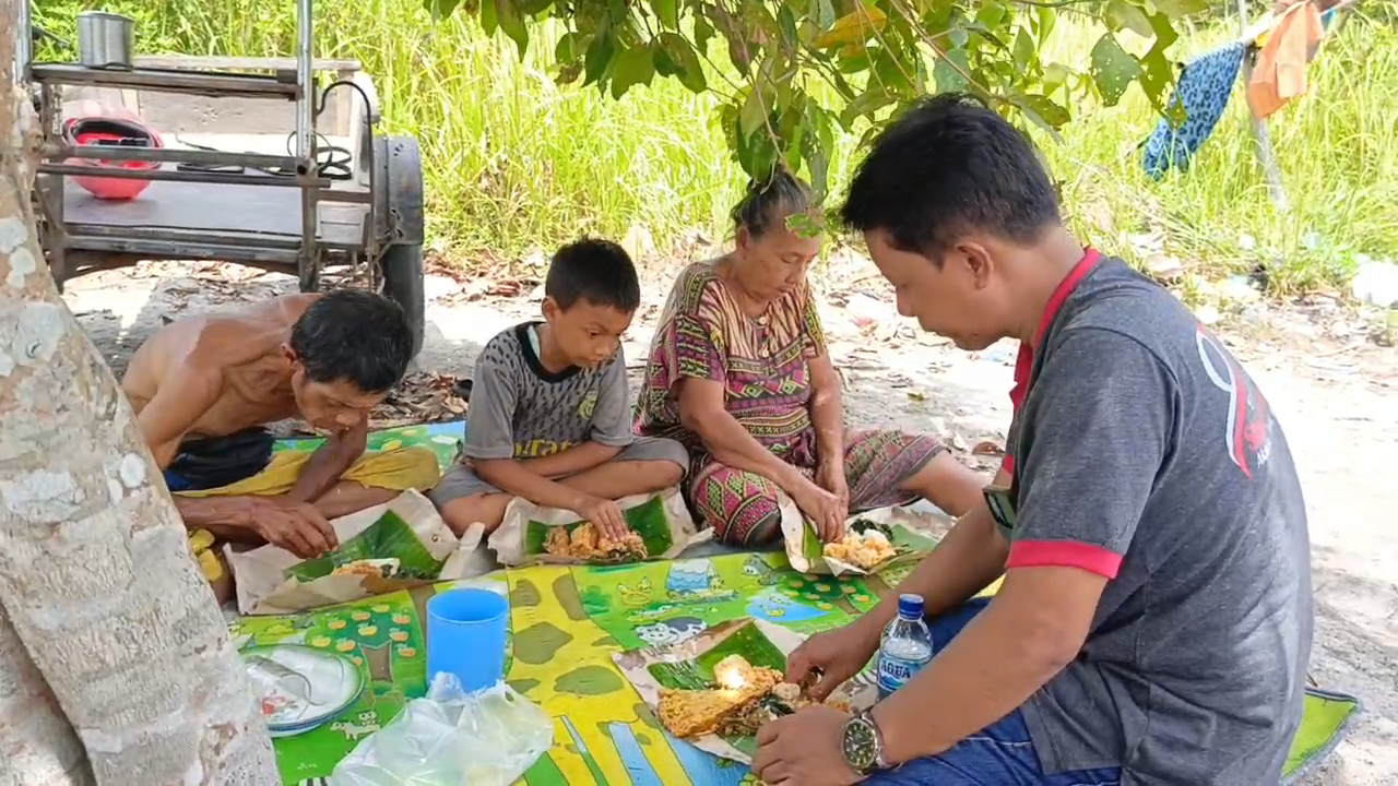 Ketua SMSI Sergai Zuhari makan nasi bungkus bersama nek Poniyah dan Kek Ponirem ditemani seorang cucu persis depan rumah di bawah Pohon Mangga dengan cuaca yang cukup panas,Minggu (11/5/2025).